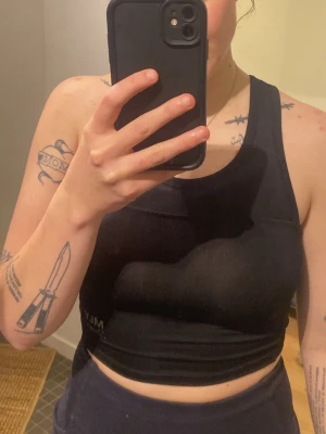 Svart sportig linnetopp från MLY Sports - Säljer en svart, croppad linnetopp från MLY Sports. Toppen har en sportig design med breda axelband och rund halsringning. Perfekt för träning eller chill dagar. Materialet är stretchigt och följsamt för maximal rörelsefrihet.