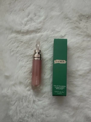 La Mer Lip Volumizer 7 ml - Lyxig läppvolymgivare från La Mer i en elegant grön förpackning. Produkten är 7 ml och designad för att ge fylligare och mjukare läppar. Perfekt för dig som vill ha en exklusiv touch till din sminkrutin.