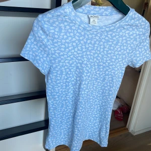 Blommig ljusblå t-shirt från Monki - Supersöt ljusblå t-shirt från Monki i storlek XXS med vitt blommigt mönster. T-shirten är ribbad, har rund halsringning och korta ärmar. Aldrig använd.