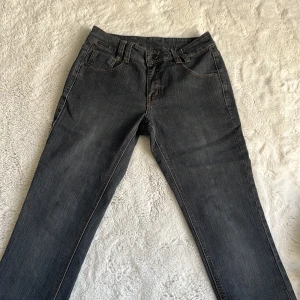 Mörkgrå jeans från KappAhl, stl 38 - Snygga mörkgrå jeans från KappAhl med klassisk femficksdesign och kontrastsömmar. Jeansen har normal passform och raka ben, tillverkade i mjukt bomullsjeansmaterial. Perfekta för en chill och stilren look.