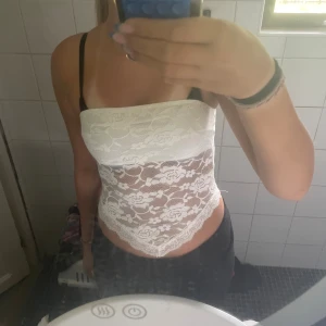 Vit spets bandeau tubtopp - Säljer en vit bandeau tubtopp i spets med blommigt mönster. Toppen är ärmlös och har en snygg v-formad nederkant. Perfekt för dig som vill ha en feminin och trendig look. Superfin att styla med jeans eller kjol! Från shein i storlek xs!❣️