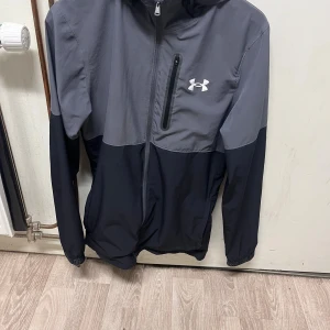 UNDER ARMOUR WINDBREAKER - Hejsan 👋🏼  Nu är det dags att sälja min Under Armour windbreaker jacka. Denna är perfekt ifall man gillar att träna utomhus eller bara allmänt gillar att bära den. Jackan har inga defekter såsom hål, slitningar eller liknande, den är i helt perfekt skick och väldigt bra omhändertagen i allmänt. Om du är intresserad eller har frågor så tveka inte på att höra av dig :)  Nypris: 760 💸 