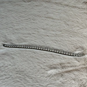 Glittrigt tennisarmband i silver - Snyggt tennisarmband i silverfärg med gnistrande stenar längs hela bandet. Klassisk och stilren design som ger en lyxig känsla. Perfekt för dig som vill addera lite extra bling till din look.