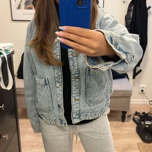 Oversized ljusblå jeansjacka från Zara  - Säljer en oversized ljusblå jeansjacka från Zara med stora fickor framtill och knappar längs hela framsidan. Jackan har en avslappnad passform och klassisk denimlook, perfekt att slänga på sig över en hoodie eller t-shirt.