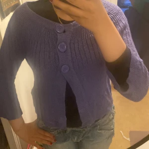 Lila kofta från Vero Moda med knappar - Säljer en lila stickad kofta från Vero Moda. Koftan har tre stora matchande knappar framtill och är ribbstickad med trekvartsärm. Super bra skick använt en gång tidigare och inga fel. 