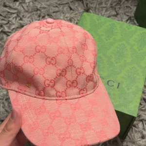 Rosa keps med-mönster - Exklusiv rosa keps från med ikoniskt monogram i ton-i-ton. Kepsen är tillverkad i bomull och har en klassisk böjd skärm. Snygg detalj med liten guldfärgad logga på sidan. Perfekt accessoar för att lyfta din outfit med lyxig känsla.