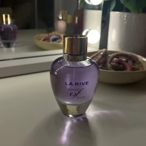 La Rive Wave of Love parfym - Snygg parfymflaska från La Rive i modellen Wave of Love. Flaskan är rundad och har en lila ton med en elegant guldfärgad kork. Perfekt att ha på sminkbordet för en fräsch och feminin känsla💓💓
