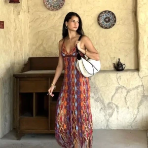 Färgglad långklänning i stickad look från Zara stl large - Säljer en bohemisk långklänning med stickad känsla och färgstarkt mönster i rött, lila, blått och orange. Klänningen har v-ringad hals, smala axelband och ett unikt hålmönster som ger en cool festivalvibe. Perfekt för dig som gillar att sticka ut med din stil!