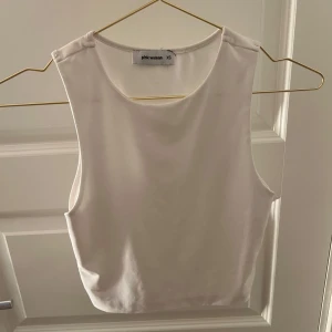 Vit croppad linnetopp från Pink Woman - Säljer en stilren vit croppad linnetopp från Pink Woman. Toppen är ärmlös med rund halsringning och har en tight passform som framhäver midjan. Perfekt till jeans eller kjol för en fräsch och enkel look.
