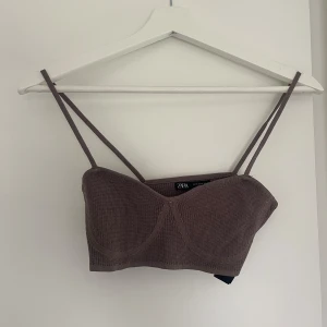 Brun ribbad stickad topp från Zara - Supersnygg brun stickad topp från Zara med tunna axelband och ribbad struktur. Croppad modell som sitter tight och kan användas under exempelvis kavaj!!🤎🤎🤎