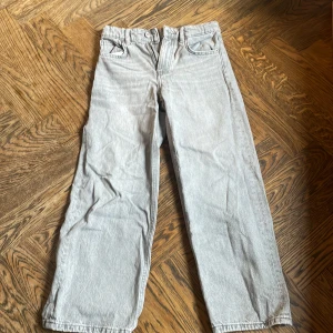 Grå jeansbyxor från Zara, wide fit - Snygga ljusgrå jeansbyxor från Zara i storlek 134. Byxorna har en rak och lite vidare passform med klassiska fem fickor och knappgylf. Perfekta för en chill och trendig look. Tillverkade i mjukt bomullsmaterial.