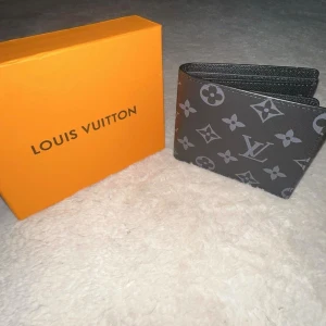 Svart handväska med orange box - Snygg svart handväska med stilren design och detaljer i silver. Kommer med en ikonisk orange box som ger exklusiv känsla. Perfekt storlek för det viktigaste och passar till många outfits.