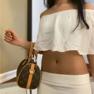 Vit topp - Säljer en vit, croppad tubtopp med offshoulder-design. Toppen har en luftig och flowy passform med lätt rynkad kant upptill. Perfekt för dig som gillar en chill och trendig stil på sommaren. Materialet känns lätt och bekvämt mot huden.