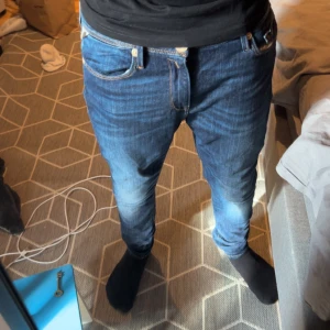 Mörkblå Replay jeans slim fit - Säljer ett par mörkblå jeans från Replay med klassisk femficksdesign och snygga slitningar framtill. Jeansen har en slim passform och är tillverkade i mjukt denimtyg med Replay-logga på bakfickan. Perfekta för dig som gillar stilrena och bekväma jeans.