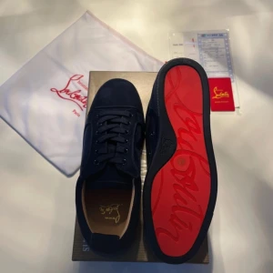 Mörkblåa mockaskor med röd undersida - Ett par lyxiga mörkblåa mockaskor med röd undersida. Kvitto, box, kort och påse ingår.