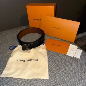 (ÄKTA) Louis Vuitton reversible belt 95cm - Snyggt vändbart Louis Vuitton-bälte i svart och brunt skinn med ikoniskt LV-spänne i metall. Svarta sidan har diskret monogrammönster, medan den bruna sidan är stilren och slät. Kommer med originalpåse, box och kvitto. Finns liten flaw som syns på bild 5, bara att jeansen skrapar emot bottnen. Inget som syns.  Går ej att få tag på idag, riktigt stilrent. Har kvitto och allt OG. Där är även ett extra hål gjort med proffesionellt verktyg. 