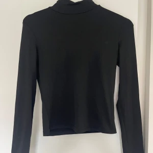 Svart polotröja med lång ärm - En stilren svart polotröja med lång ärm. Tröjan har en klassisk hög krage och är gjord i ett mjukt material som sitter snyggt på kroppen🖤🖤🖤