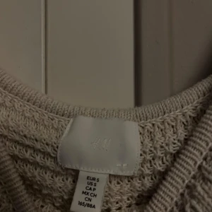 Beige stickad topp med volang - Superfin beige stickad topp från H&M med volangdetaljer runt halsringningen och axlarna. Toppen är ärmlös och har en croppad passform som ger en trendig look. ❤️❤️