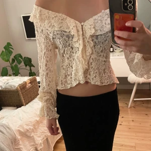 Offshoulder spetsblus med volang -  offshoulder blus i ljus spets med volangdetaljer och knappar framtill. Blusen är croppad och har långa ärmar. Man kan även knäppa toppen så den inte är off shoulder 💗