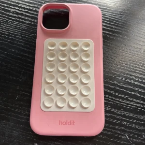 Rosa mobilskal från Holdit - Säljer detta fina holdit skal för iPhone 13. Tror även de passar för andra. Sugproppgrejen på går att ta av. Köpt för ca 1 månad sen. 