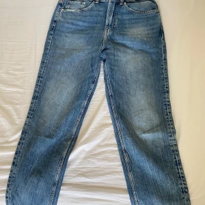 Blå raka jeans med normal passform - Klassiska blå jeans med raka ben och normal passform. Jeansen har fem fickor, bälteshällor och en snygg tvättad look. Perfekta för dig som gillar en avslappnad stil och vill ha ett par tidlösa jeans i garderoben.