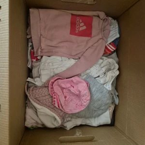 Klädpaket med ytterplagg och sovsäck till vagn - Halvfull flyttlåda med kläder samt en jeans sovsäck till vagn och 3 set med jacka och byxa, 1 regnjacka, 1 overall och 1 vinterjacka. 