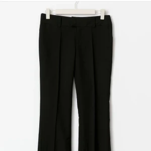 Svarta kostymbyxor med bootcut GINA TRICOT - Snygga svarta kostymbyxor från gina tricot med bootcut-silhuett och pressveck. Byxorna har hällor för bälte och klassisk midja. Perfekta för en clean och stilren look. Medelhög midja. Säljer pga köpte för stor storlek.