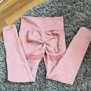 Rosa seamless leggings i S - Säljer ett par rosa seamless leggings med hög midja och scrunch-detalj bak. De är tillverkade i ett stretchigt material av 90% polyamid och 10% elastan, vilket gör dem perfekta för träning eller chill. Snygg passform och ribbade detaljer längs benen.