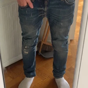 Blå slim fit jeans från Nudie - Säljer ett par blå slim fit jeans från Nudie med slitningar och snygga detaljer på bakfickorna. Perfekta för dig som gillar en smalare passform! Detta är en limited model med slitningar som inte säljs längre, där av priset! De är i jättebra skick (9,5/10), utan några defekter! Mitt pris är 899 där av att dem är limited och inte säljs längre! Nypris på dem när dem såldes var 2399! Priset är inte hugget i sten och kan diskuteras! Det är bara att skriva vid minsta fråga:)