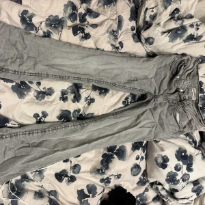 Grå jeans med fickdetaljer - Snygga grå jeans med raka ben och coola fickdetaljer bak. Jeansen har klassisk femficksdesign, silverfärgade knappar och markerade sömmar. Perfekta för dig som gillar en stilren look med lite edge. 