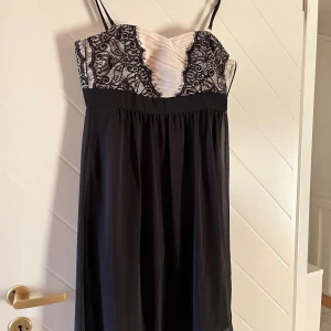 Svart och vit klänning från Esprit - Supersnygg svart och vit klänning från Esprit med tunna axelband. Överdelen har vit drapering och svart spetsdetalj, medan kjolen är svart och faller rakt ner. Perfekt för dig som gillar eleganta detaljer och stilren look.