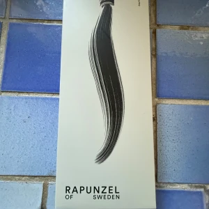Rapunzel of Sweden ponytail 60cm - Clip-in hästsvans i äkta hår från Rapunzel of Sweden.  medium volym. Fästes enkelt med dold kam och kardborre. endast använd vid test av håret sedan har den legat i en silkes mössa under tiden, aldrig tvättat eller hårdvårds produkter. Inte klippt eller annorlunda från orginalet Äkta hår Färg brown ash blonde balayage 60 cm