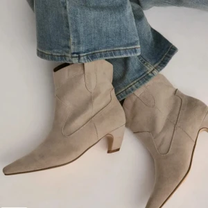 Beige cowboy boots med spetsig tå - Snygga (SLUTSÅLDA‼️ beige cowboy boots i mocka med spetsig tå och låg klack. Bootsens design har klassiska sömmar och en stilren siluett som ger en cool western vibe. Perfekta att matcha med jeans för en trendig look.