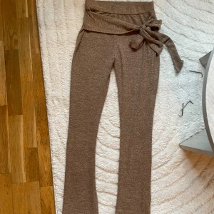 Bruna stickade byxor med knyt - Mysiga bruna stickade byxor med hög midja och bred knytning i midjan. Storlek M , osäker på märke