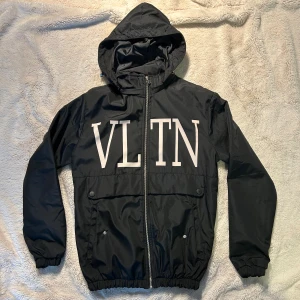 Svart valentino jacka  - Svart vindjacka från Valentino med stor vit VLTN-logga över bröstet i storlek M 