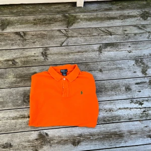Orange pikétröja från Ralph Lauren - Snygg orange pikétröja från Ralph Lauren i storlek small och har den klassisk kragen. Tillverkad i mjuk bomull som är skön mot huden. Extremt bra skick och sälj enbart pga storlek!!