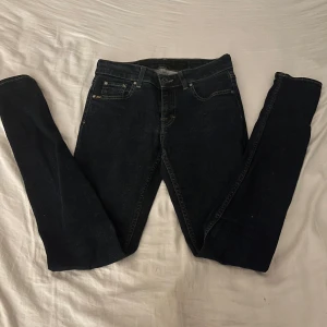 Tiger of Sweden mörkblå jeans slight - Mörkblå jeans från Tiger of Sweden i modellen Slight. Klassisk femficksdesign med snygga kontrastsömmar och raka ben. Tillverkade i Italien av mjukt jeanstyg som sitter riktigt bra. Perfekta för dig som gillar stilrena och tidlösa jeans.