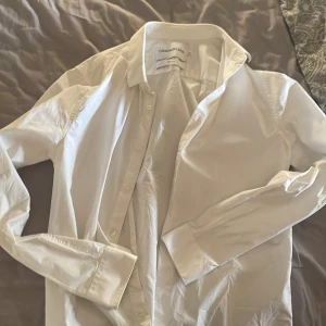 Vit slim fit skjorta Calvin Klein Jeans - Vit skjorta från Calvin Klein Jeans i slim fit-modell. Klassisk design med krage och knappar framtill samt långa ärmar med manschettknappar. Skjortan är tillverkad i bomull och har en stilren look som passar perfekt till jeans eller chinos.