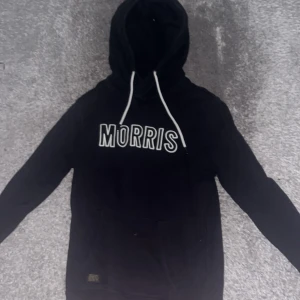 Svart hoodie från Morris med tryck - Svart hoodie från Morris med vit logga framtill och vita snören i huvan. Hoodien är i fint skick nästan oanvänd, hör av er vid frågor!🙌