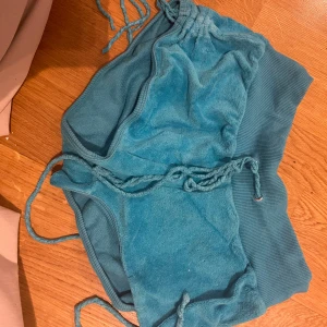 Turkosa frottéshorts Calzedonia - Turkosa shorts från Calzedonia i mjuk frotté med bred ribbad midja och snörning i sidorna. Perfekta för sommardagar eller strandhäng. Snygg och avslappnad passform med coola detaljer.