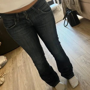 Mörkblå bootcut jeans från Lee - Säljer ett par mörkblå jeans från Lee med klassisk femficksdesign och snygga slitningar. Jeansen har bootcut-ben och normal passform. Materialet är jeans med kontrastsömmar och Lee-logga på bakfickan.