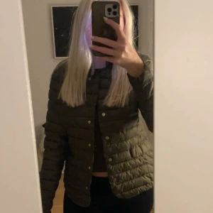  dunjacka - Snygg olivgrön dunjacka med guldiga knappar framtill. Jackan är quiltad och har en klassisk, normal passform med långa ärmar. Helt oanvänd. 
