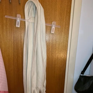 Vit fleecehalsduk med fransar - Mysig och enkel vit halsduk i fleece med fransar i ändarna. Perfekt för att hålla värmen under kyliga dagar nu till hösten och vintern. Den är lätt att matcha med olika jackor.