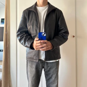 Brun skinnjacka från Aldini - En snygg mörkbrun skinnjacka från Aldini med dragkedja framtill. Jackan har bred krage, två sidofickor och är helfärgad utan mönster. Säljer åt min pojkvän 💓 Sparsamt använd, inga defekter. Denna kommer nog bara bli snyggare med tiden! 