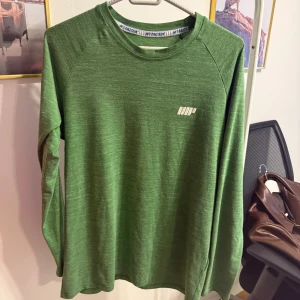 Grön långärmad tröja från MyProtein - Snygg grön långärmad tröja från MyProtein med diskret logga på bröstet och tryck i nacken. Tröjan har en enkel, sportig design och är tillverkad i ett mjukt och lätt material som passar perfekt till träning eller chill dagar.