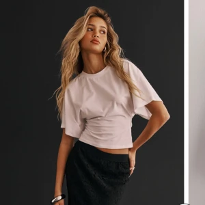 Vit Nelly topp, round neck wide sleeve tee - Säljer en vit croppad topp med rund halsringning och extra vida, korta ärmar. Toppen har en tight passform över midjan som ger en snygg siluett. Perfekt att styla med både jeans och kjol för en trendig look. Säljer pga för lite användning, använd en gång. nypris är 249kr. 