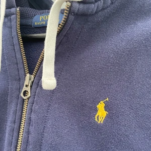 Ralph Lauren Zip hoodie - Säljer en snygg mörkblå hoodie från Polo Ralph Lauren med dragkedja 🔥Skick 8/10 Inga hål bara att den varit använd 🙌 Passar lite mindre ksk för dig runt 168-175 | vid funderingar tveka it att dma 💭pris går såklart att diskutera 🙌
