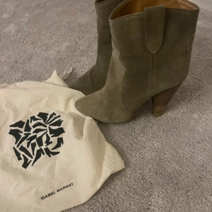 Olivgröna boots från Isabel Marant - Snygga olivgröna boots från Isabel Marant i mocka med spetsig tå och hög klack. Klassisk western-inspirerad design med träklack och dekorativa sömmar. Perfekta för dig som vill ha en cool och trendig look.