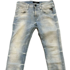 Replay ljusblå anbass jeans - Snygga ljusblå jeans från Replay med slitna detaljer och klassisk femficksdesign. Jeansen har raka ben och coola broderade bakfickor. Perfekt för dig som gillar en avslappnad och trendig look. Materialet är mjukt och stretchigt jeans.