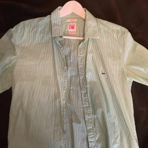 Lacoste LIVE Skjorta i grön och vit färg - Lacoste skjorta som är grön och vit i färg väldigt bra skick fast på bilderna ser skitigare pris kan diskuteras 